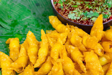 Fried dumplings are placed on a banana leaf./ Fried dumplings as snacks. The sauce as an ingredient.