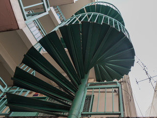 Green spiral staircase pattern view from below. Spiral stairs circle in courtyard architecture. Outdoor ladder decoration interior. Selective focus.