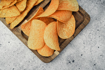 Chips, snacks and crackers on a wooden board. Fast food.