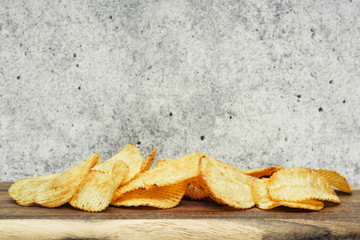 Corrugated potato chips on a wooden board. Snack, ready meal menu, junk food. Close up.
