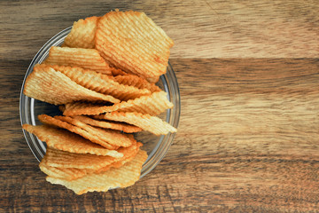 Corrugated potato chips on a wooden board. Snack, junk food. Close up.