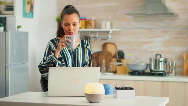 Drinking coffe and working with aromather apy essential oils diffuser in the kitchen. Aroma health essence, welness aromatherapy home spa fragrance tranquil theraphy, therapeutic steam, mental health