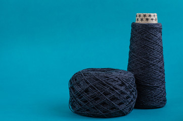cone and ball of gray wool yarn on turquoise background. copy space