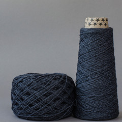 cone and ball of gray wool yarn on light gray background