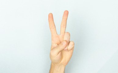 2 fingers. Two thumbs up. Woman shows two fingers. Peace sign. Fingers on a blue background