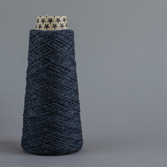 cone of gray wool yarn on light gray background. copy space