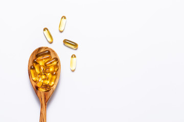 Omega 3 cod liver oil capsules in the wooden spoon on white background with copy space for your design. immunity support capsules. Health care concept. - obrazy, fototapety, plakaty