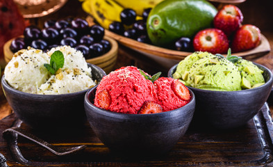 vegan ice cream made with organic fruits, with tropical fruits in the background, flavors of strawberry, banana, jabuticaba and avocado