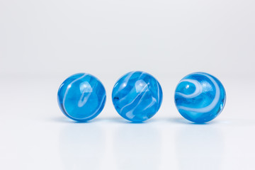 group of transparent glass marbles in blue with white swirls