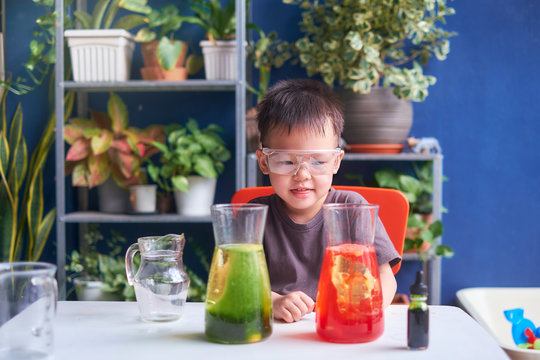 Happy little Asian school kid studying science, making DIY Lava Lamp Science Experiment with oil, water and food coloring, Kid-friendly fun and easy science experiments at home concept