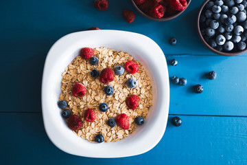 Flat lay view of oat flake with blueberry and raspberry over blue wooden backdrop