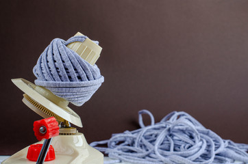 hand plastic wool winder at work, gray yarn ball, brown background. prepair for knitting, crochet. handmade concept