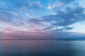 Beautiful sunrise on the lake with dramatic blue clouds .