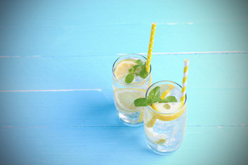 Lemon juice mixing soda no-alcohol with slide lemon and mint in the glass on blue wooden background with copy space. Drinks for healthy this summer.
