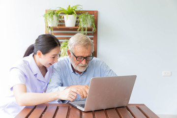 Nurse help senior retirement man working with laptop at home and feeling happy