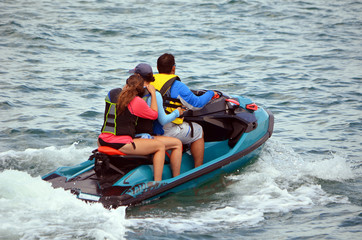 Three riding in tandem on a blue jet ski