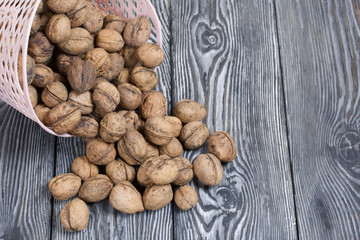An overturned basket of walnuts. Against a background of painted pine boards.