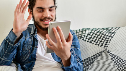 Young man using a tablet sitting on the couch in the living room at home