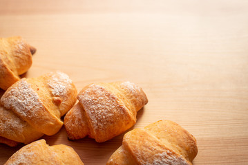 Close up picture of fresh tasty croissants on wooden table with copy space