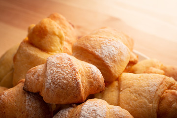 Fresh tasty croissants in plate of wooden table