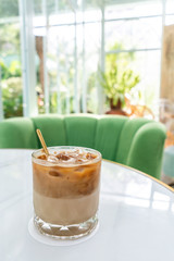 Ice coffee in a tall glass with milk poured over