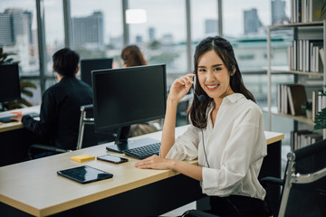 Obraz premium Asian woman customer support operator or call center with headset looking the camera and smiling.
