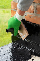 Roofer's hand in green mittens holding a brush