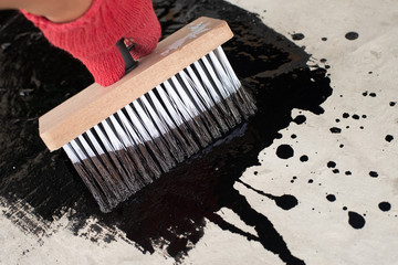 Roofer's hand in red mittens holding a brush