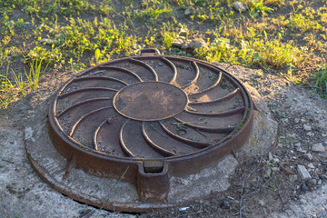 Old rusty round sewage hatchway on the lawn