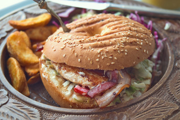 Delicious breakfast bakery - fresh sesame bagel with cream cheese, lettuce, chicken creast, tomato, ham and fried potato 