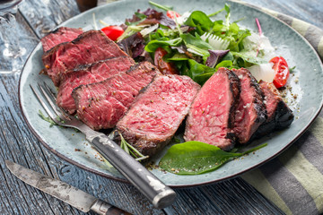 Traditional dry aged wagyu sirloin beef steak with Italian salad affered as closeup on a design plate