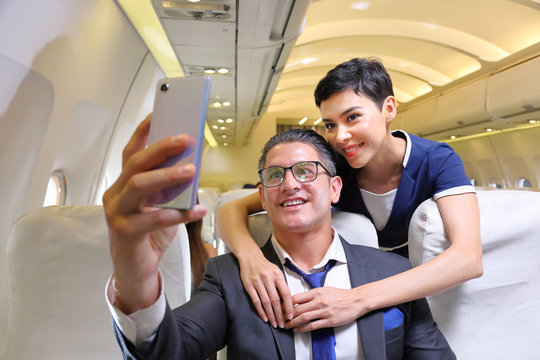 Caucasian businessman in formal wear and his partner taking selfie from cellphone in the aircraft with copy space