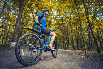 woman cyclist rides mountain bike forest trails.