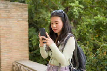 lifestyle portrait of young happy and beautiful Asian Chinese tourist woman visiting Europe during Summer holidays trip using internet mobile phone enjoying old town landscape