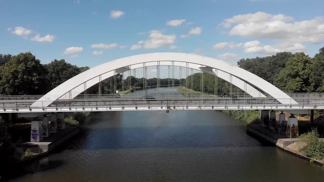 Cars and bicycles passing by on a steel bridge construction asphalt road over the Twentekanaal in Zutphen, The Netherlands, revealing in backwards aerial movement the wider surrounding