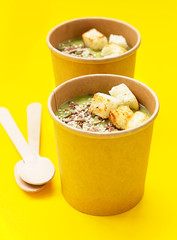 Fresh broccoli cream soup with croutons and seeds in craft containers. Soup to go, healthy food delivery.