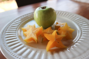 White plate with carambola and fresh apple.