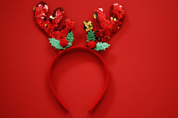 Traditional hair accessory: Christmas deer antlers on a red background. Decorated with sparkles. Merry Christmas concept. Stylish New Year card.