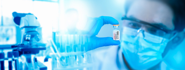 Vaccine research and Medicine infectious coronavirus 19 concept.scientist in biohazard protection clothing analyzing covid 19 in blood sample tube for test vaccine with microscope in laboratory