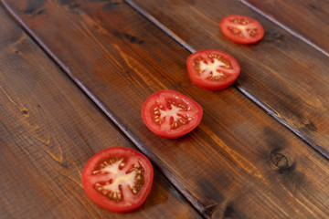 tomato slices on a brown wooden background, top view, text space, fresh vegetables