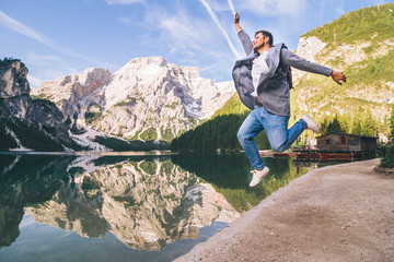 man jumping at lake beach of mountain lake