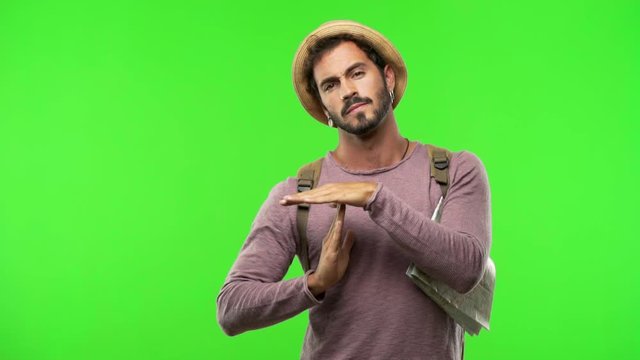 Young traveler man on chroma making a timeout gesture