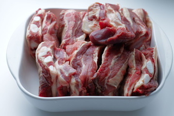 Beef ribs in a white, glass dish. Ingredient, fresh meat to cook. Veins, beef ribs, meat texture. Increase in prices for natural, farm products, imports. Meat on a plate