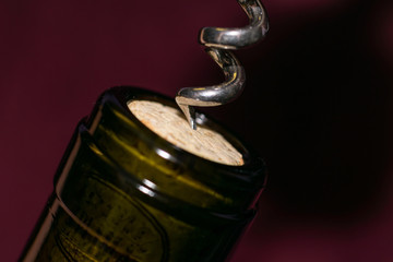 Extremely close up view of bottleneck of wine bottle and bottle-screw swirling cork. Wine bottle opening