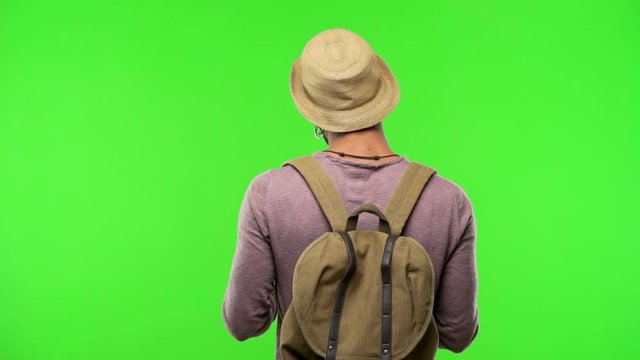 Young traveler man on chroma from behind, looking back