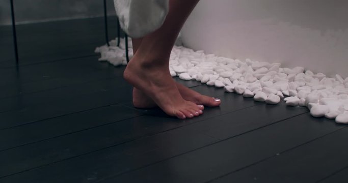 Rear Back View of Woman's Feet Entering Bathroom. Cropped Shot of Barefoot Woman Taking off White Bathrobe before Shower or Bath.
