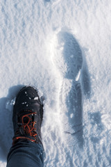 Abstract background with traces of a human foot on the snow of feet in a boot and jeans