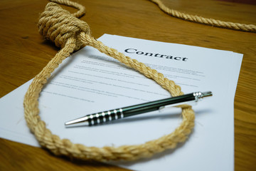 Contract with pen and rope tied in hangmans noose. Strangulation contract, unfair agreement.