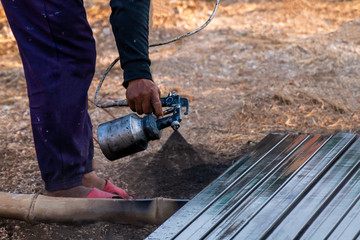 spray painting metal work, steel painters man with a spray gun in hand, laborer or labor day concept, copy space