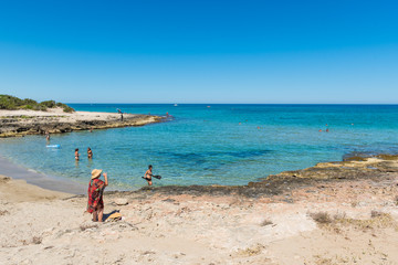 Fototapeta na wymiar Wonderful Mediterranean coast beach in Puglia, South Italy, with bathers in crystal clear water